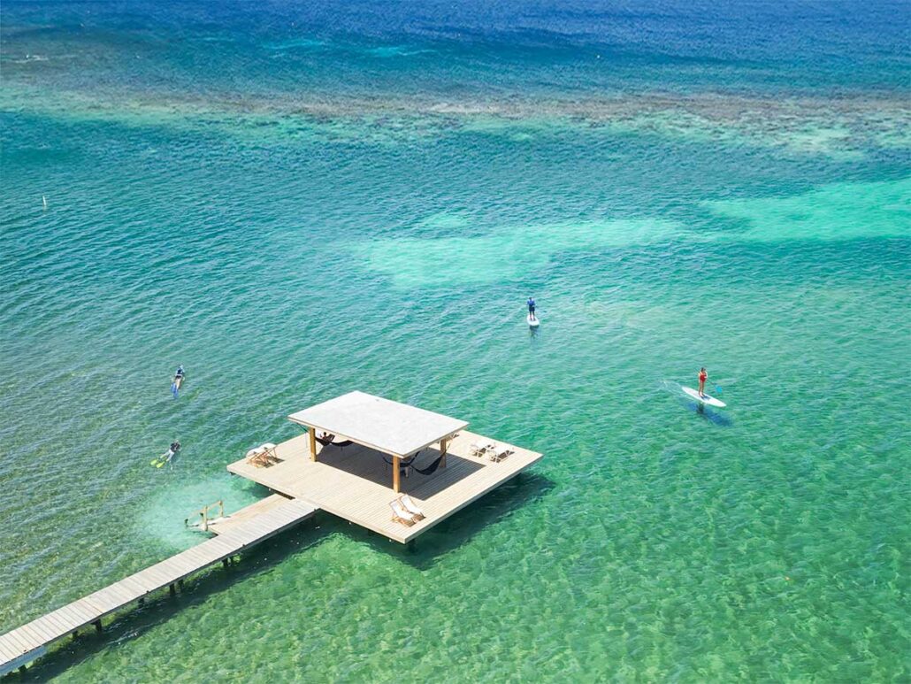Aerial view of guests snorkeling and paddleboarding in turquoise water at the end of the private 400-foot dock at Puerta Azul Roatan.