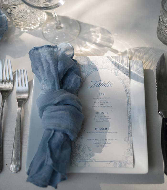 Elegant wedding reception table setting with personalized menu and blue linen napkin at Puerta Azul Roatan